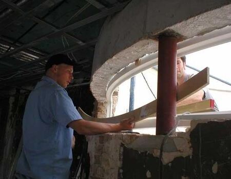 Zwei Mitarbeiter bauen ein gebogenes Isolierglasfenster ein