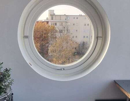 Weiße Wand mit eingelassenem runden Fenster