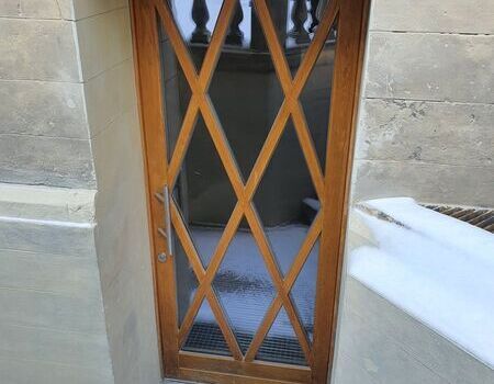 Eingangstür aus Holz mit Fenstern in Rautenform